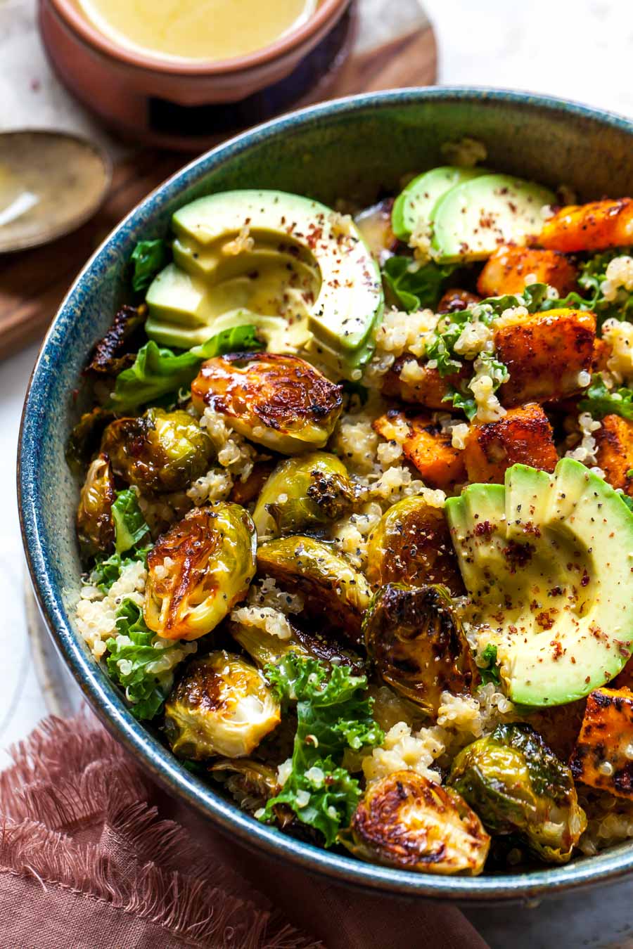 Roasted veggies in a bowl with sliced avocado