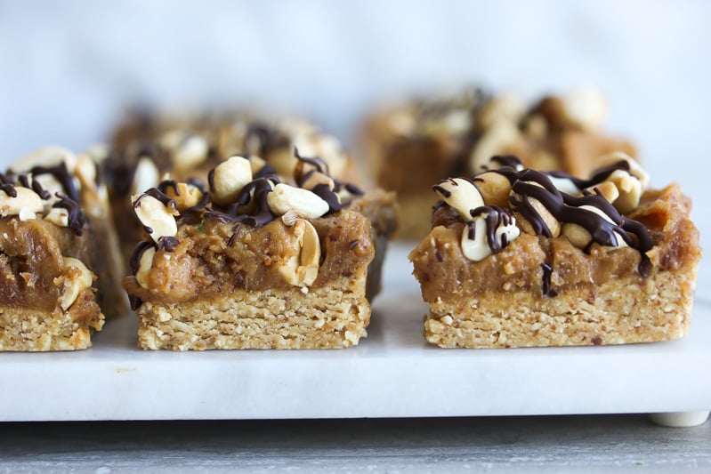 Side view of Vegan Peanut Butter Snickers Bars on a cutting board