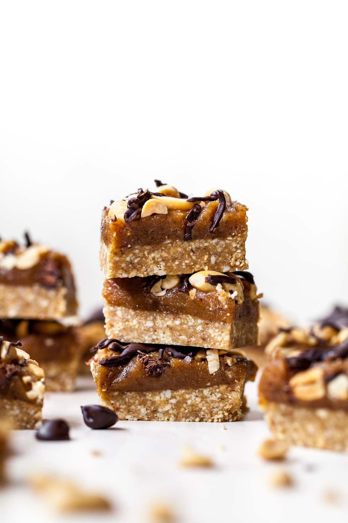 Stack of three peanut butter Snickers bars with peanuts scattered around