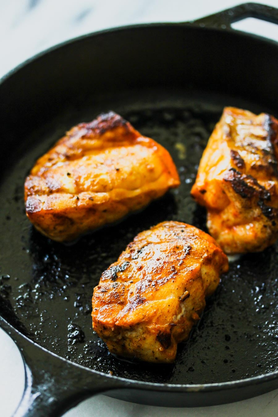 Taco-seasoned fish being sautéed in a skillet