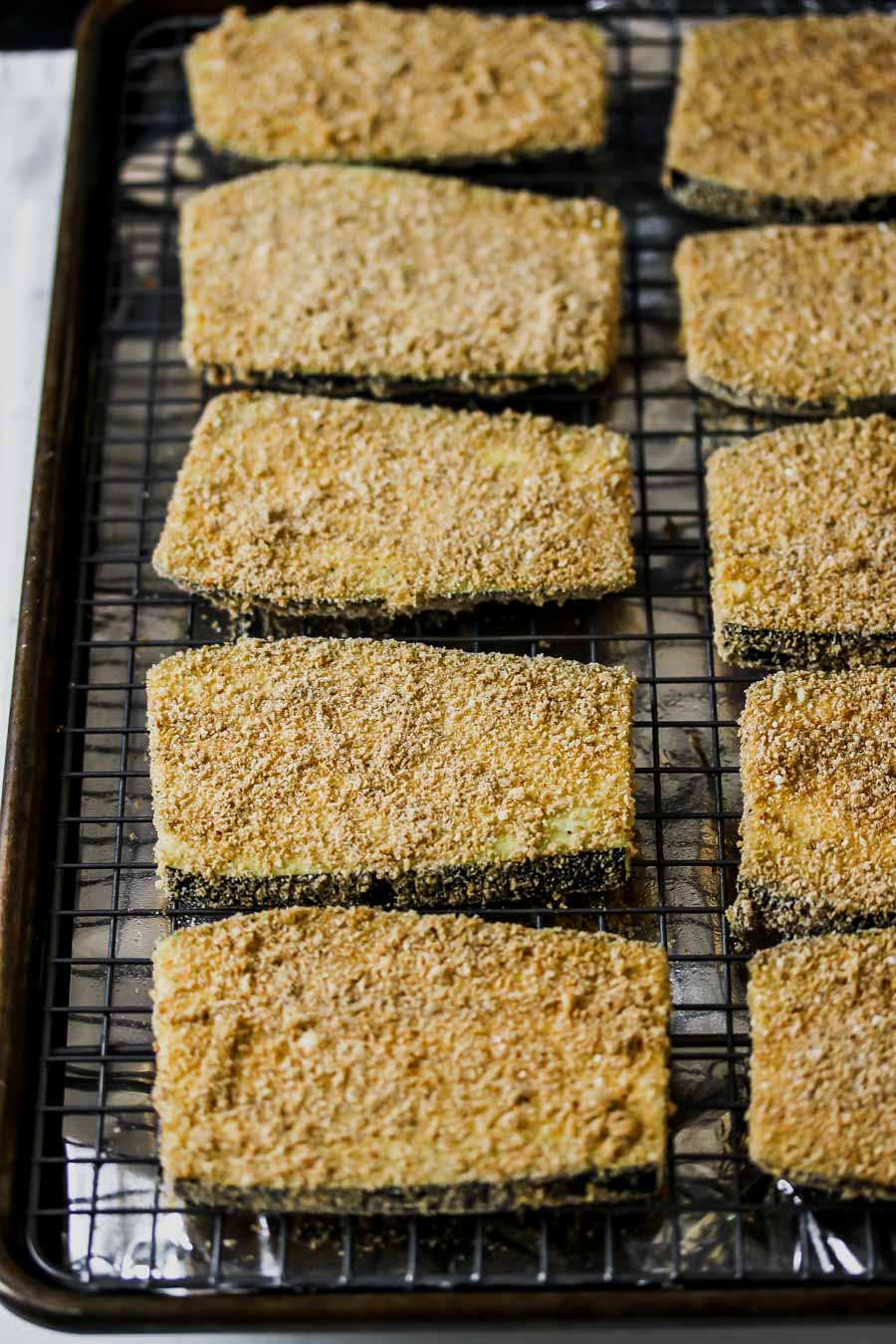 Slabs of eggplant after being dredged in egg and breadcrumb mixture