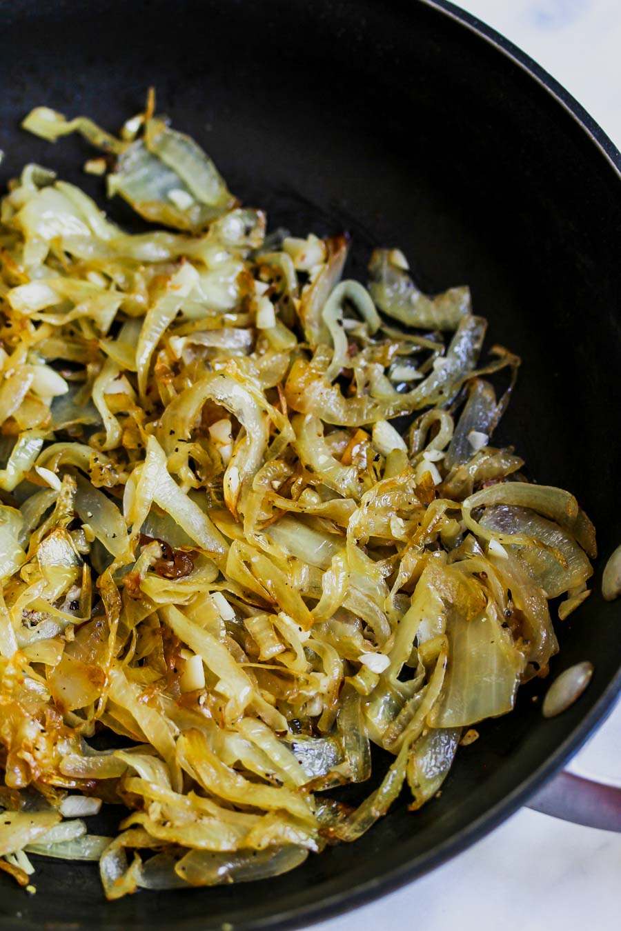 Onions being caramelized in a black skillet