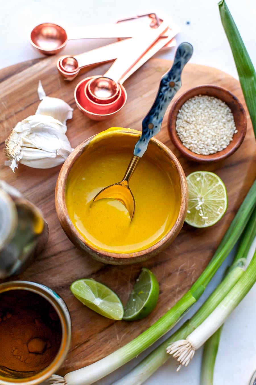 Turmeric-tahini sauce being mixed in a brown wooden bowl