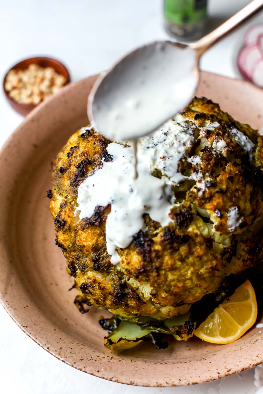 Pesto-Roasted Whole Cauliflower with Creamy Garlic Sauce