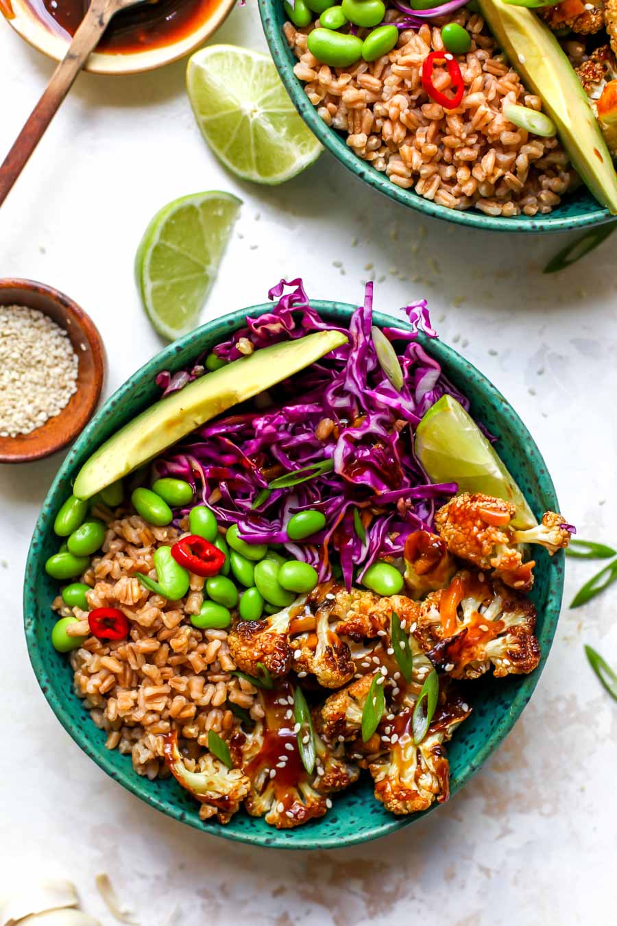 Teriyaki Cauliflower Bowls styled in a teal bowl garnishes with avocado and lime wedges.