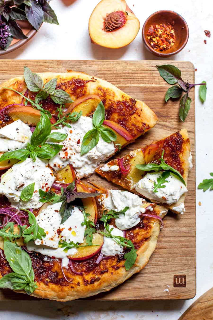 Stove top pizza with peach-BBQ sauce, fresh sliced peaches, red onion, burrata, and basil