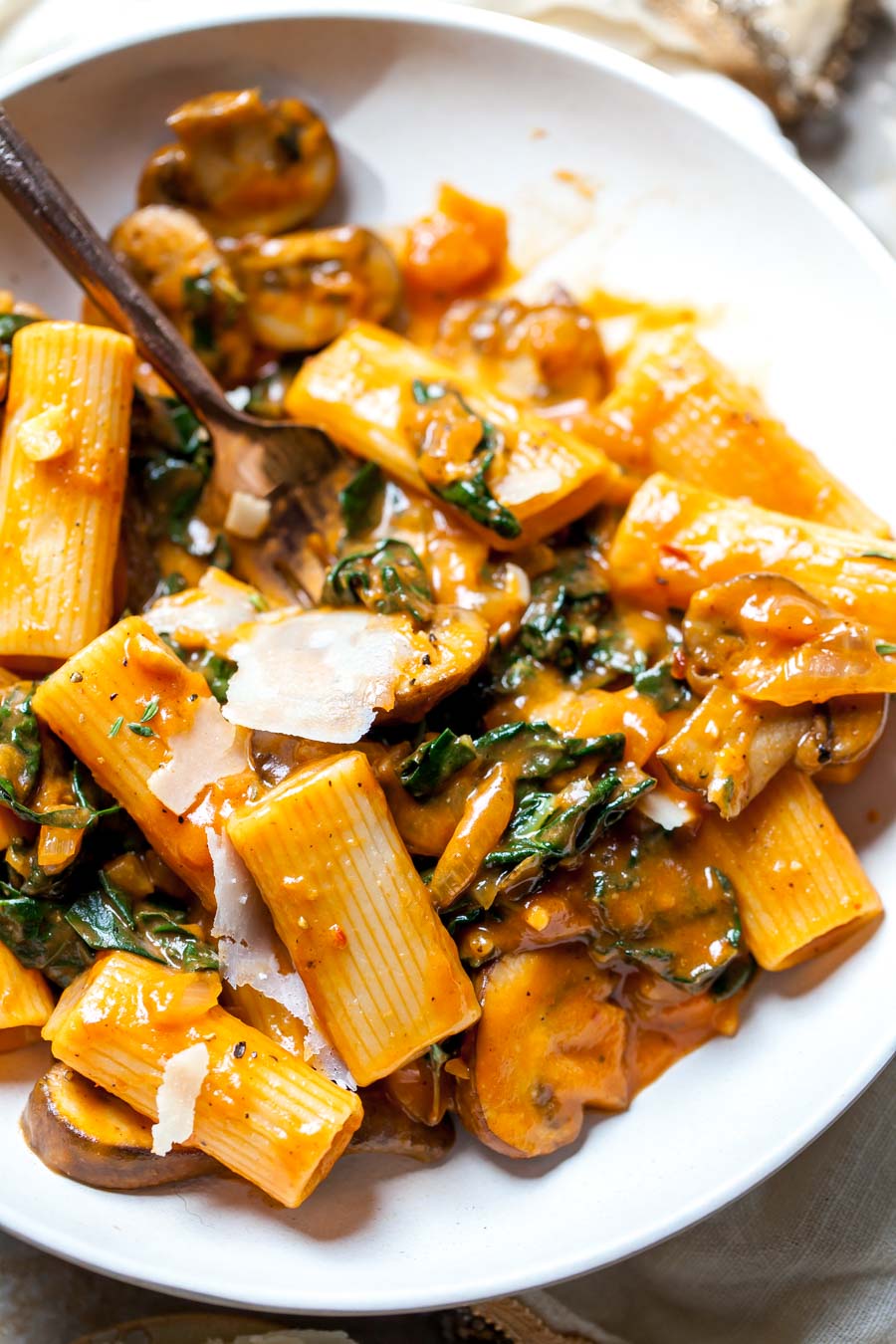 Rigatoni tossed in vegan pumpkin sauce in a white serving bowl.