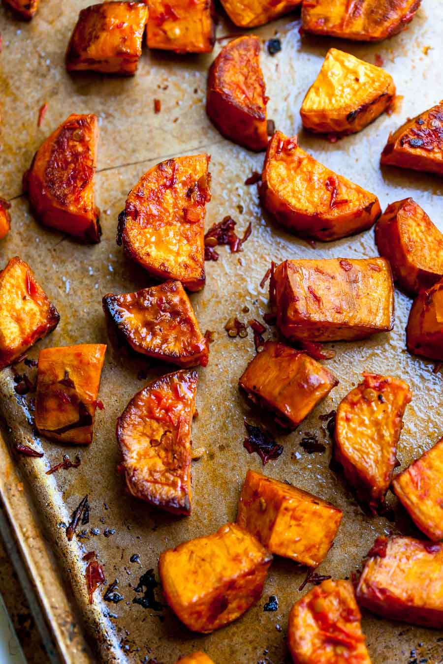 Wedges of sweet potatoes being roasted on a sheet pan