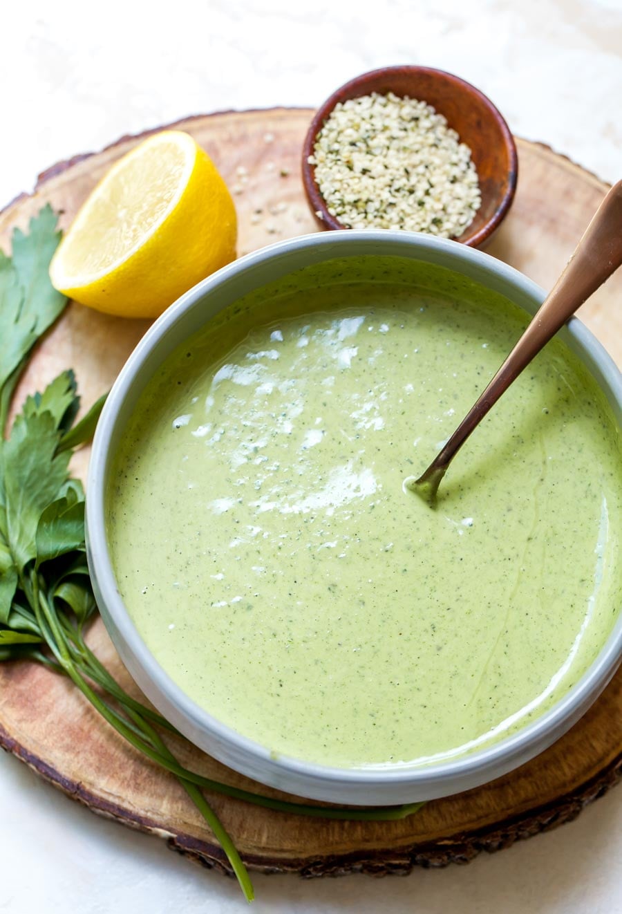 Parsley tahini dressing in a silver bowl with a spoon resting on the side