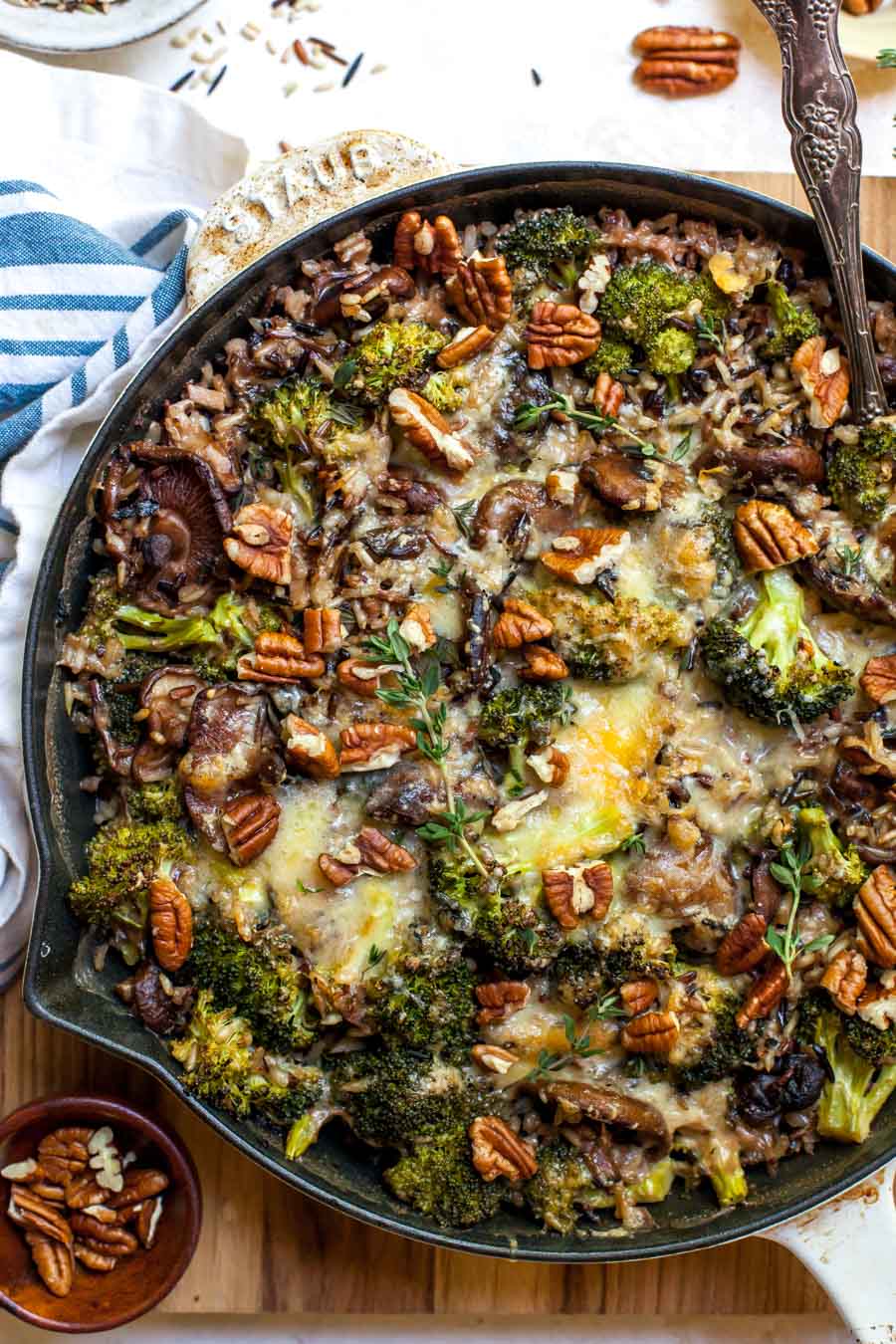 Wild rice and broccoli casserole styled in a round baking dish with a serving spoon resting on the right side.