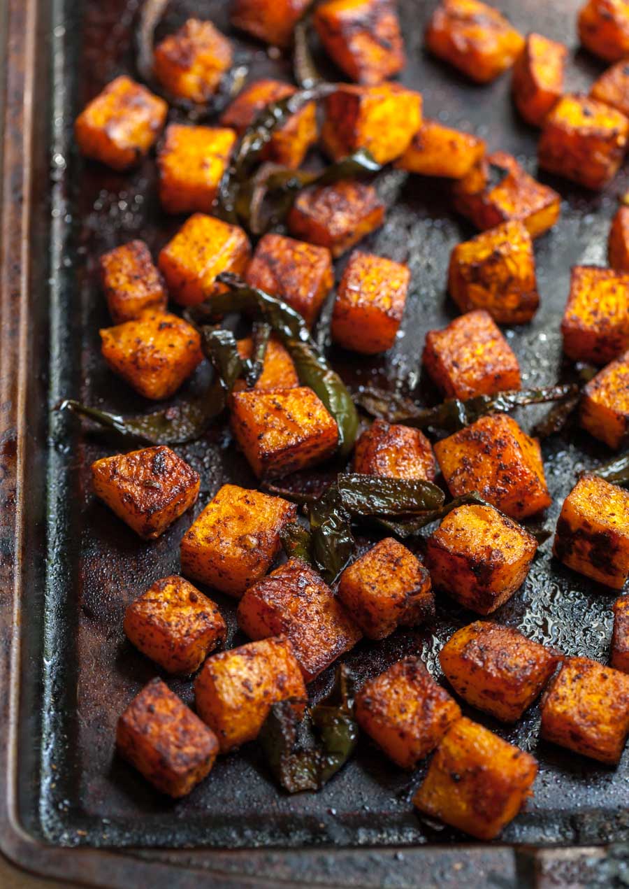 Cubes of butternut squash and poblano peppers being roasted on a sheet pan.