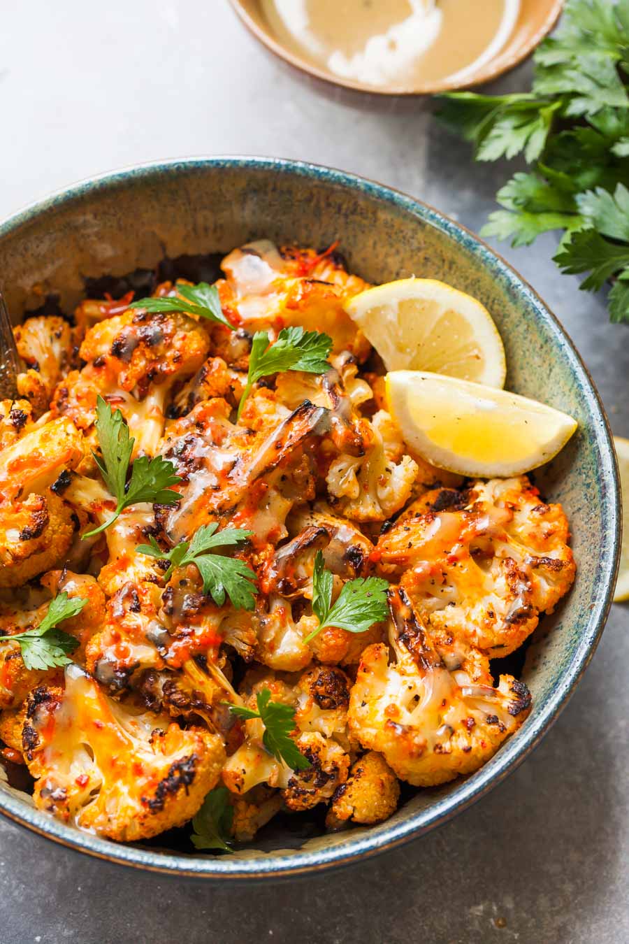 Blue and black bowl filled with moroccan cauliflower and lemon wedges