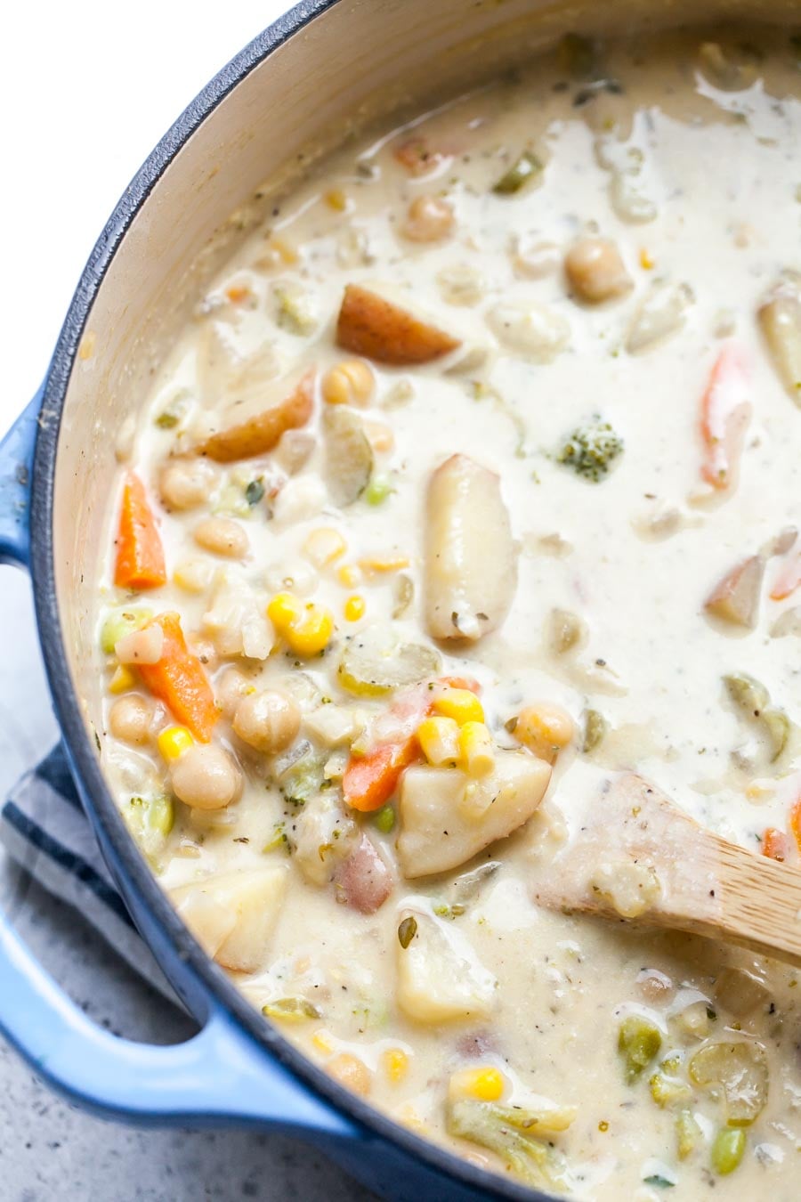 Wooden spoon stirring a pot of vegan vegetable soup.