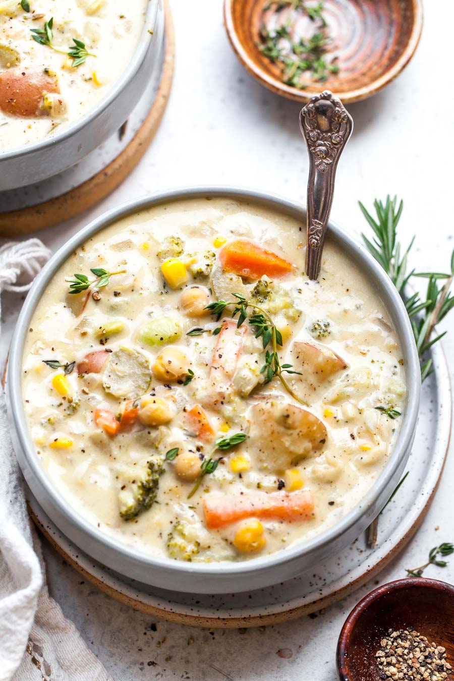 Creamy vegetable soup in a white speckled bowl with a spoon resting on the right side.
