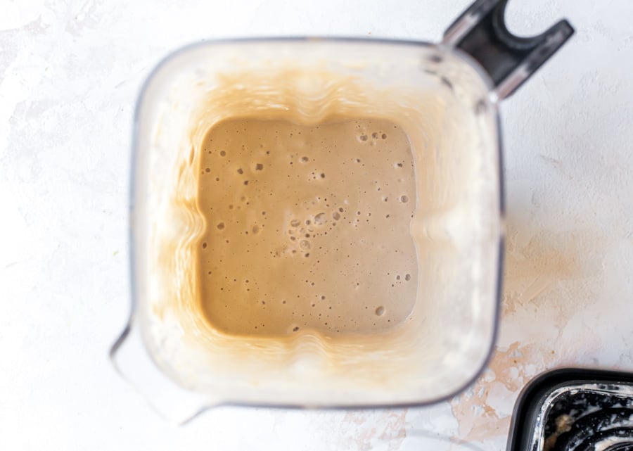 Broth and cashews being blended until smooth in a blender