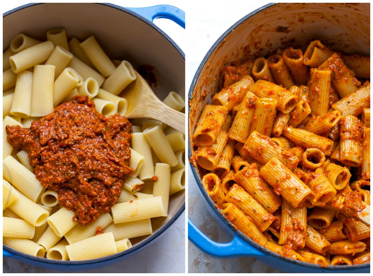 Pesto being mixed into rigatoni in a large blue pot.