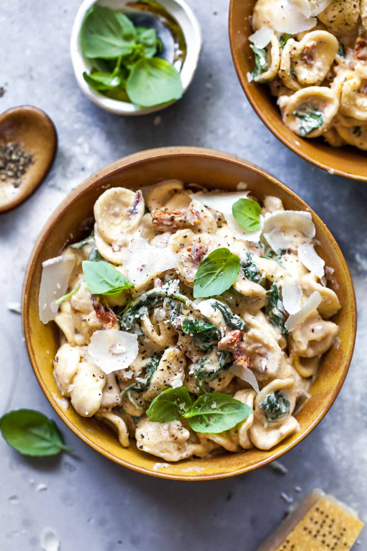 Creamy chicken pasta in a gold bowl topped with basil leaves