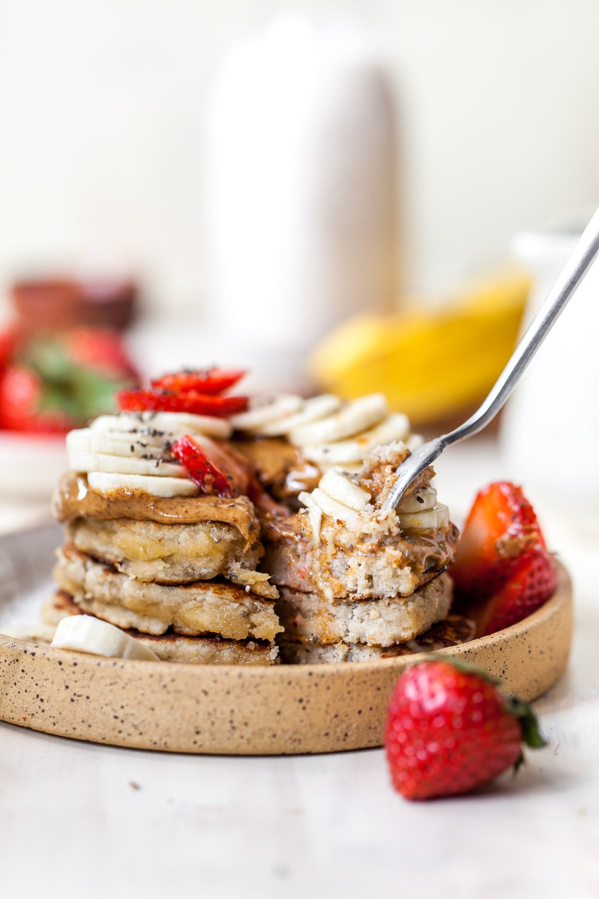 Stack of three pancakes with fork pulling out a bite