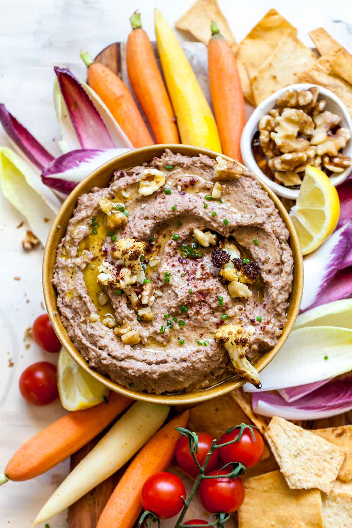 Cauliflower dip in a bowl surrounded by colorful veggies