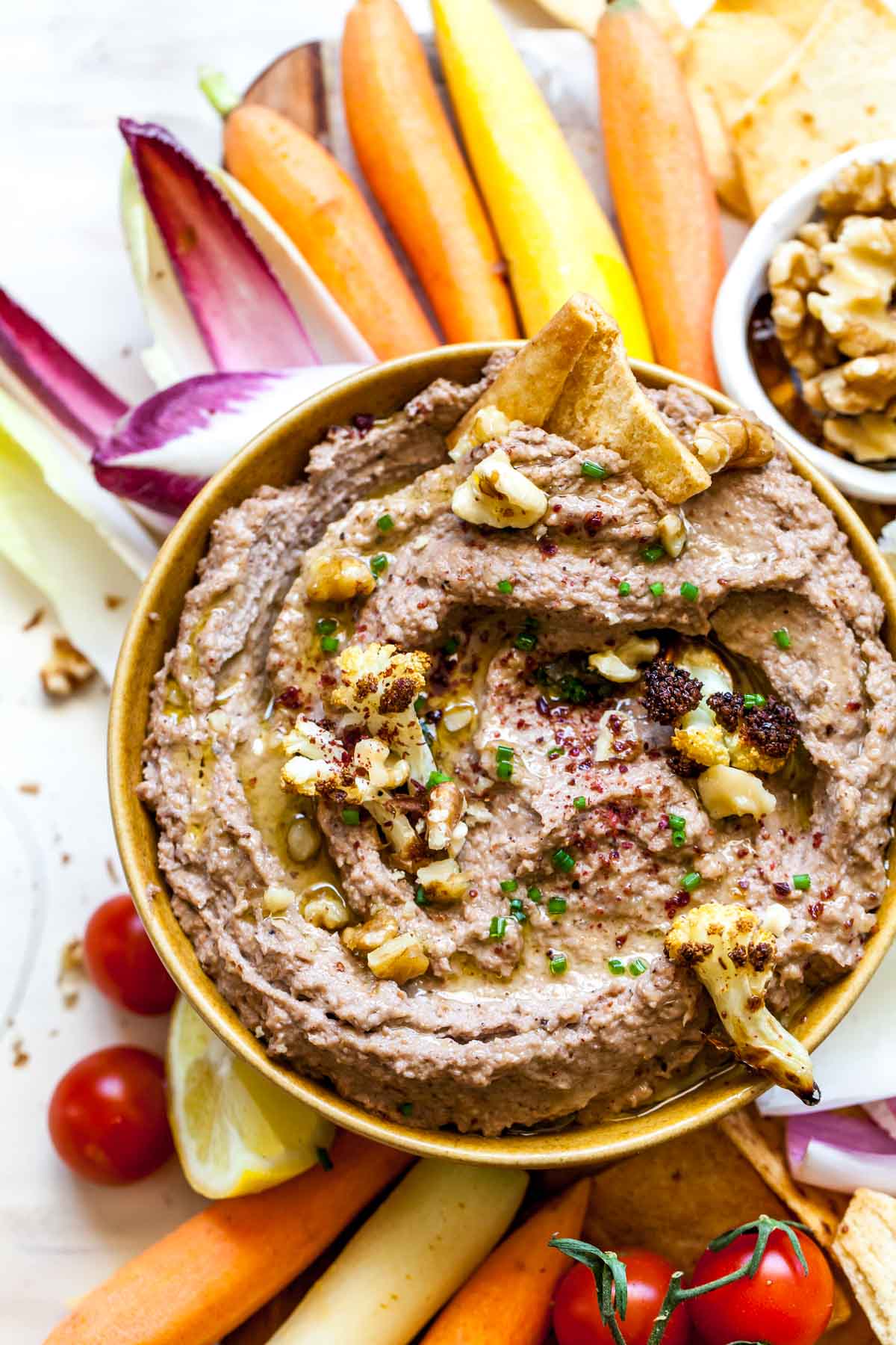 Pita chip scooping up Cauliflower Walnut Dip in a bowl