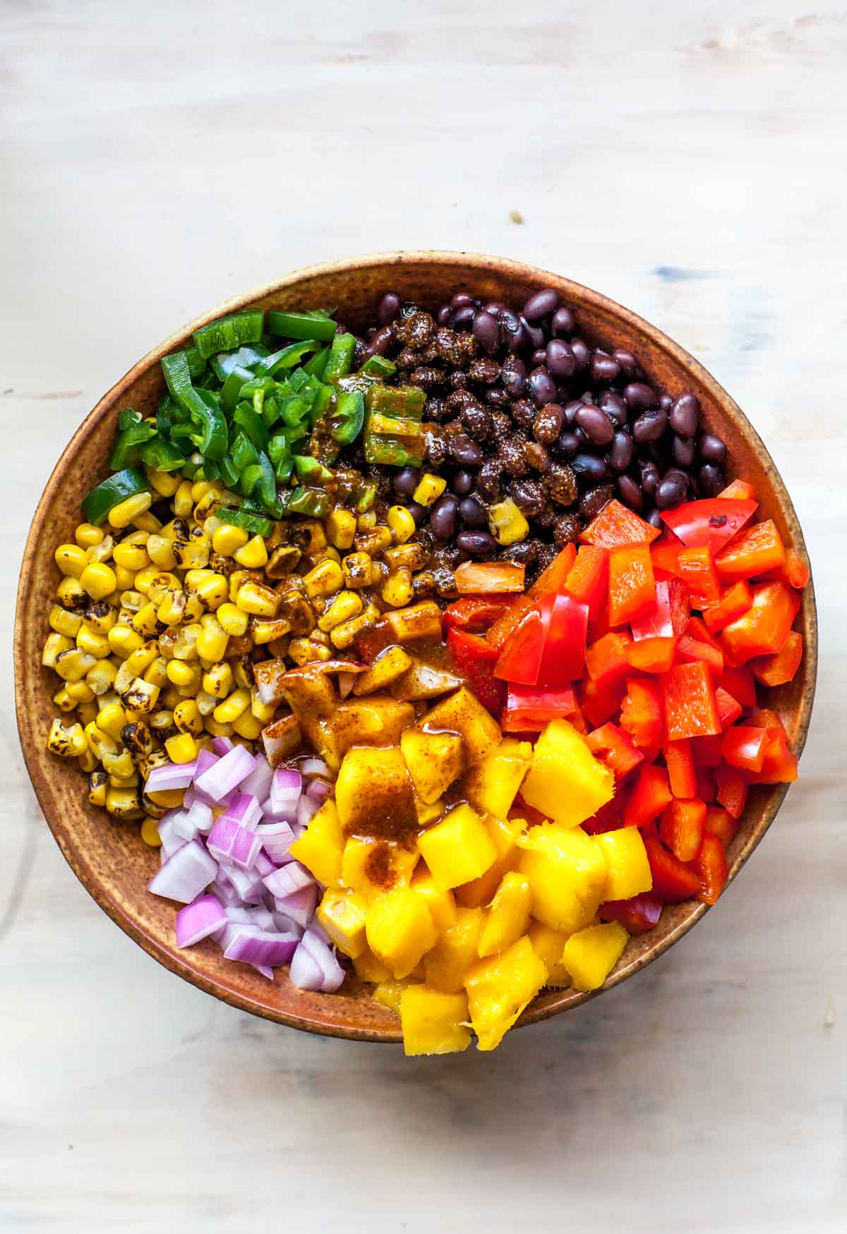 Chili-lime dressing poured over a quinoa salad in a tan bowl