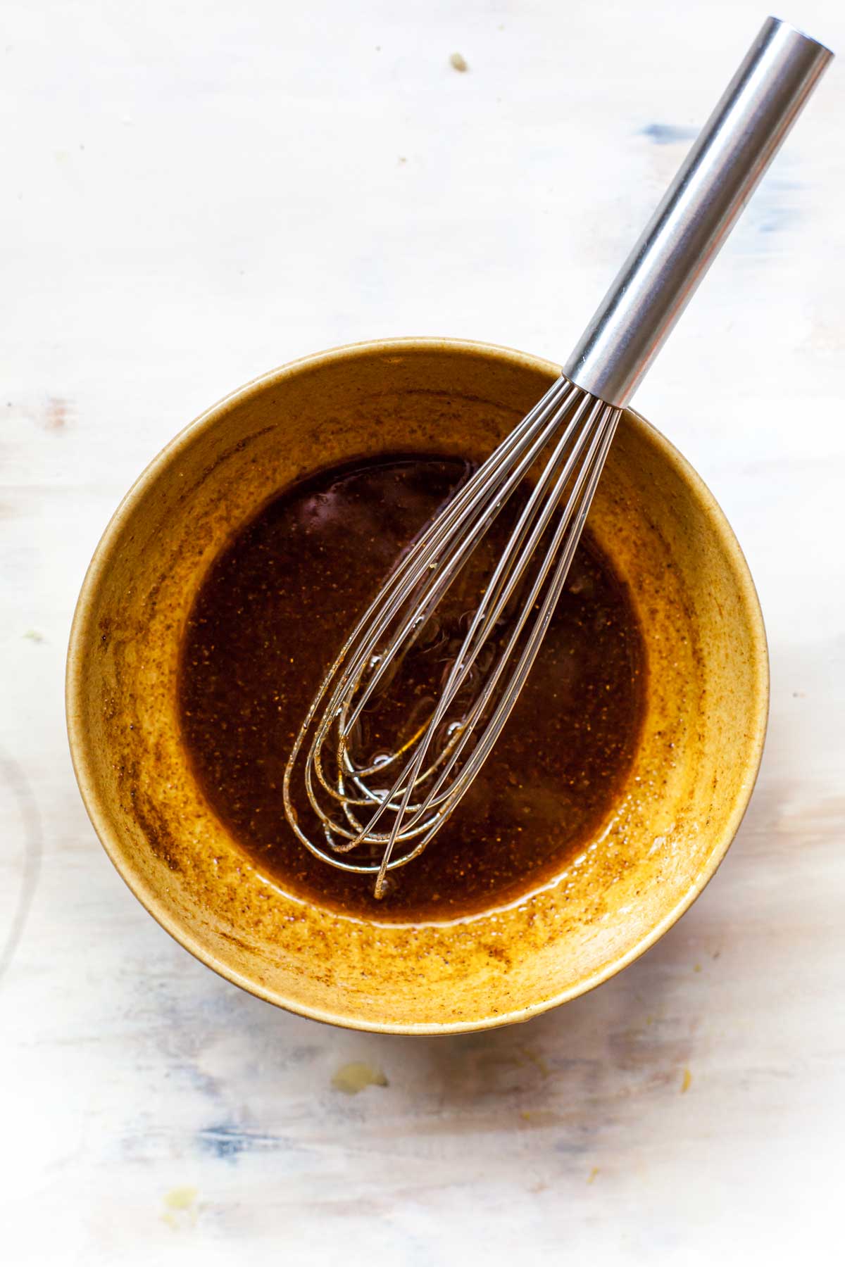 Chili-lime salad dressing in a small gold bowl with a whisk