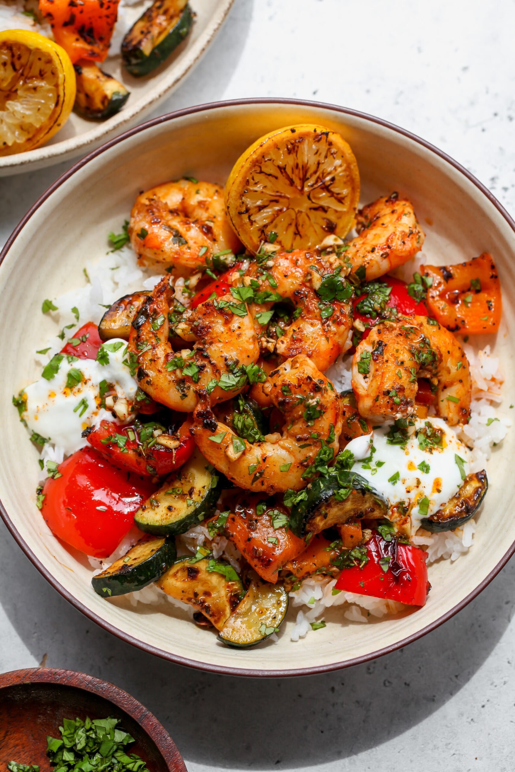 Greek Shrimp Bowl styled in a white bowl with a seared lemon wedge on the upper right side.