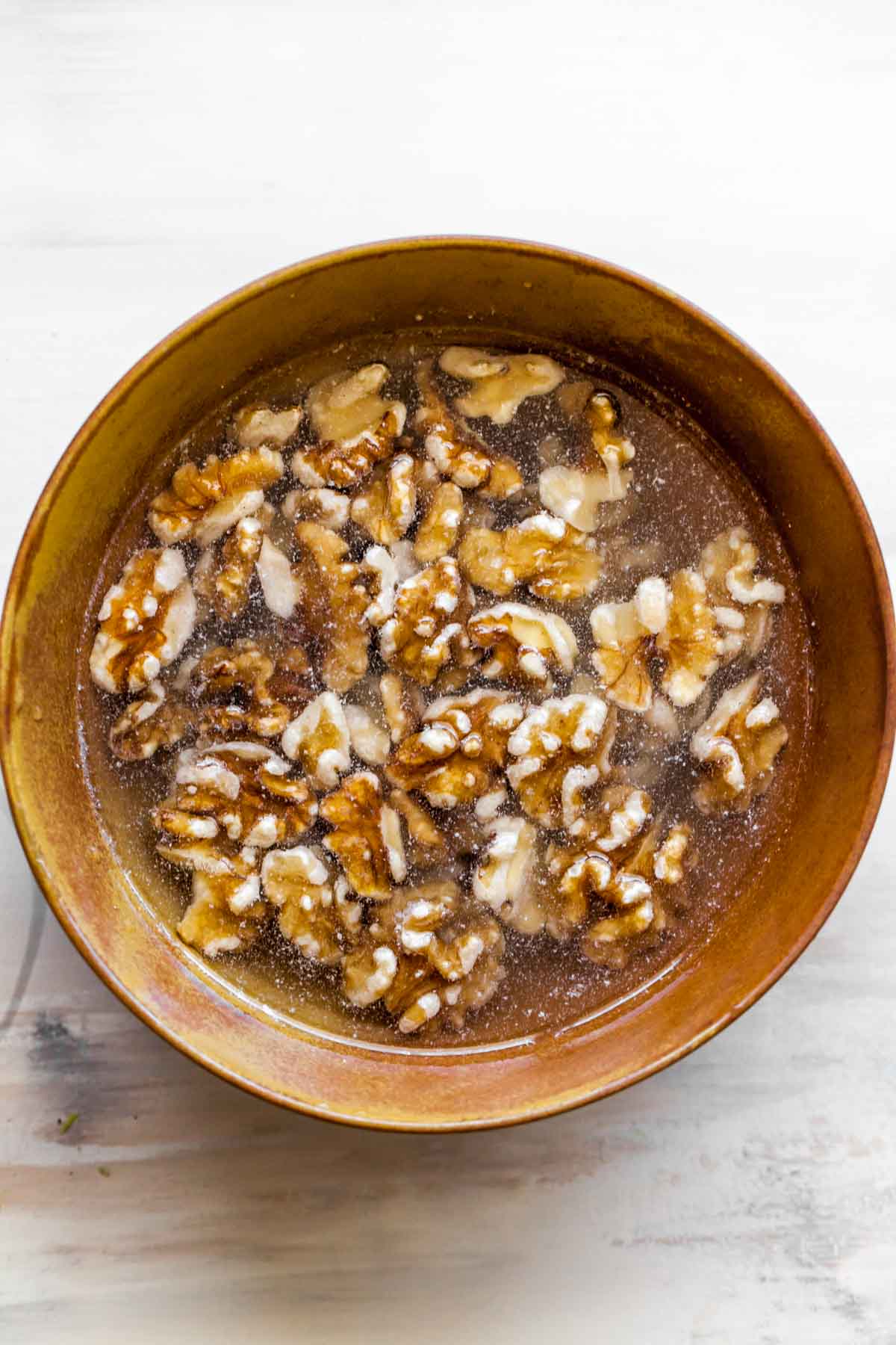 Walnuts soaking in water in a gold bowl