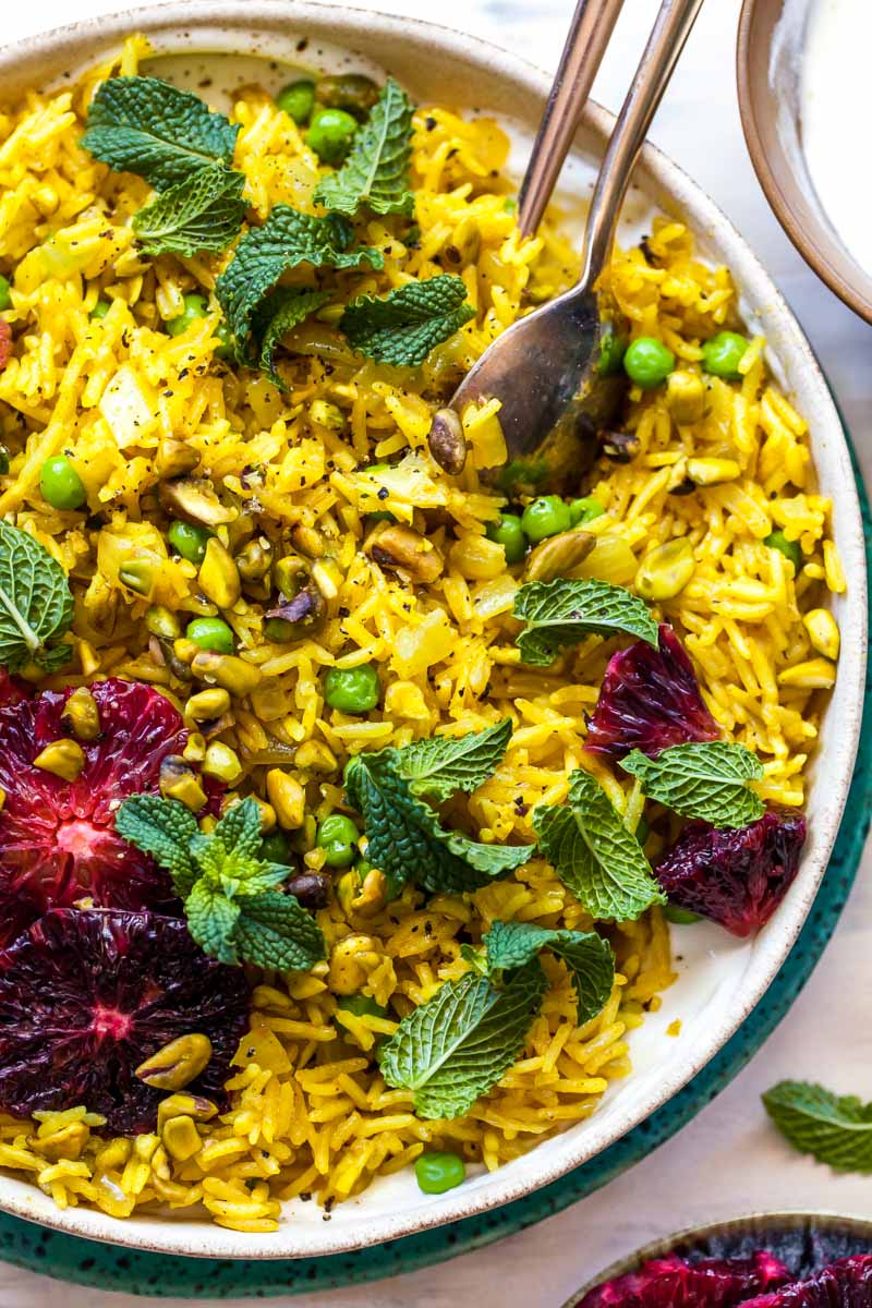 Gold spoon scooping up yellow rice out of a tan bowl