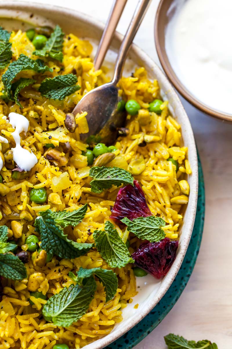 Close up of curried rice in a tan bowl with spoon propped on the side