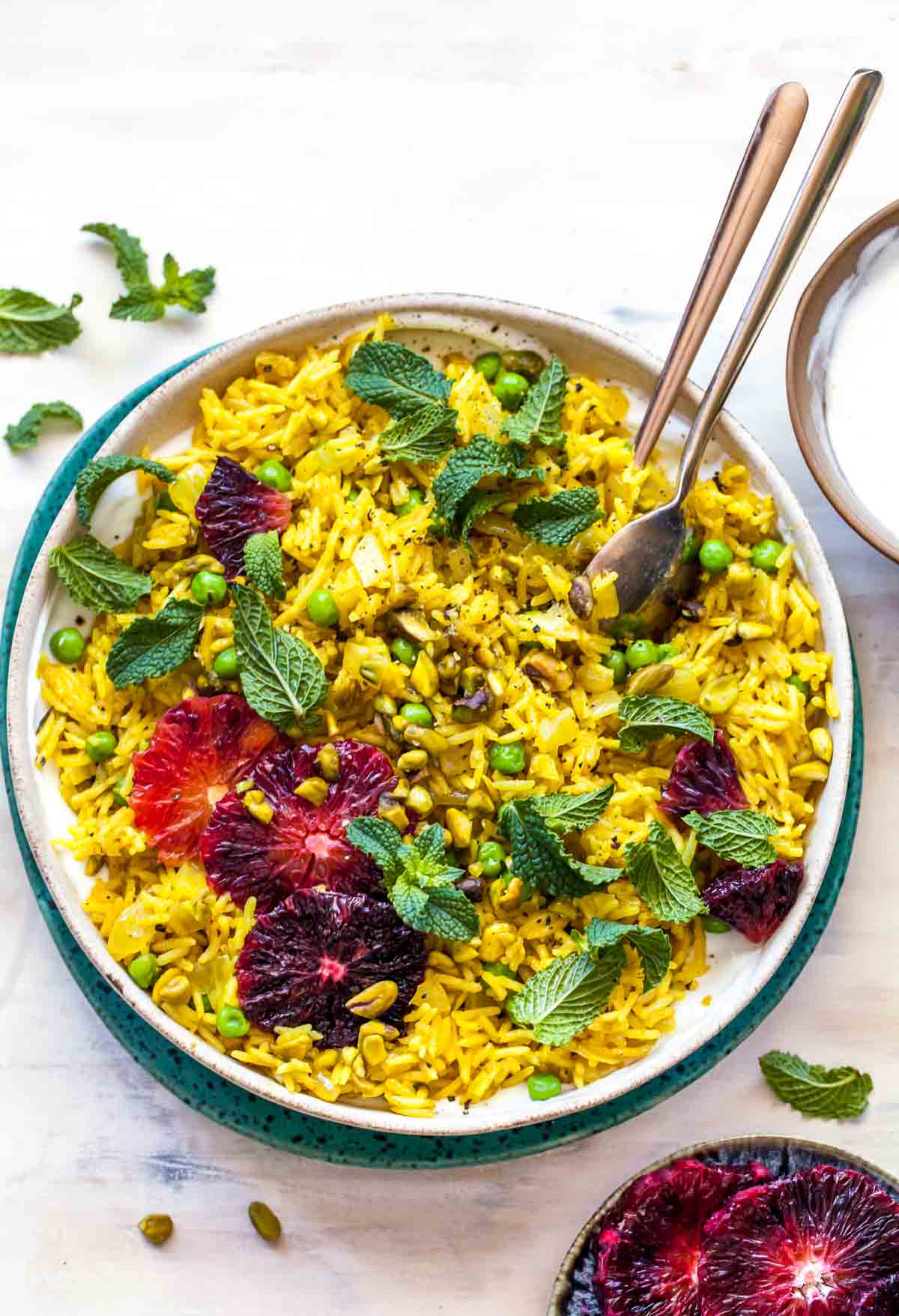Yellow basmati rice in a tan bowl topped with orange slices and mint leaves