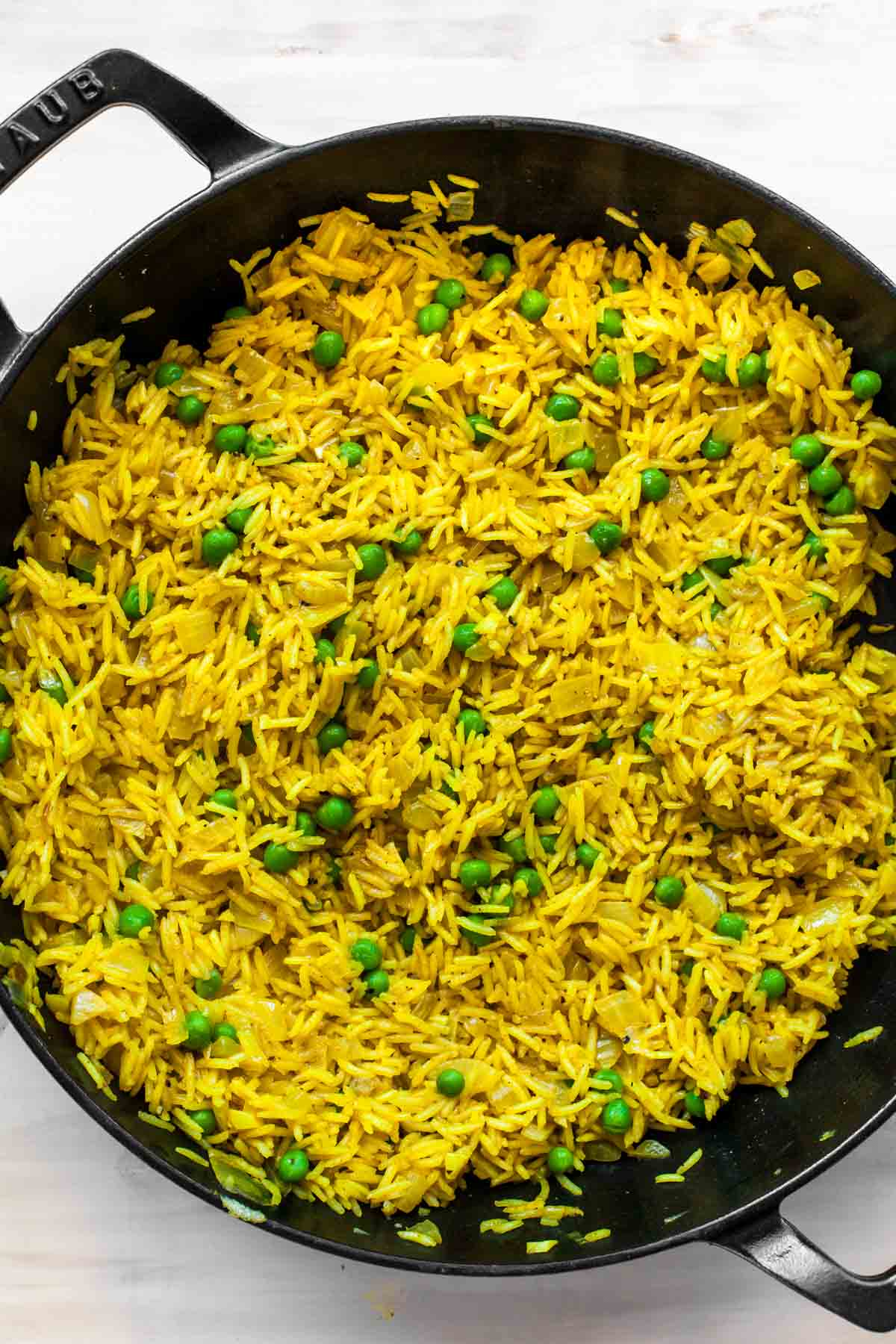 Curried white rice and peas in a large black skillet