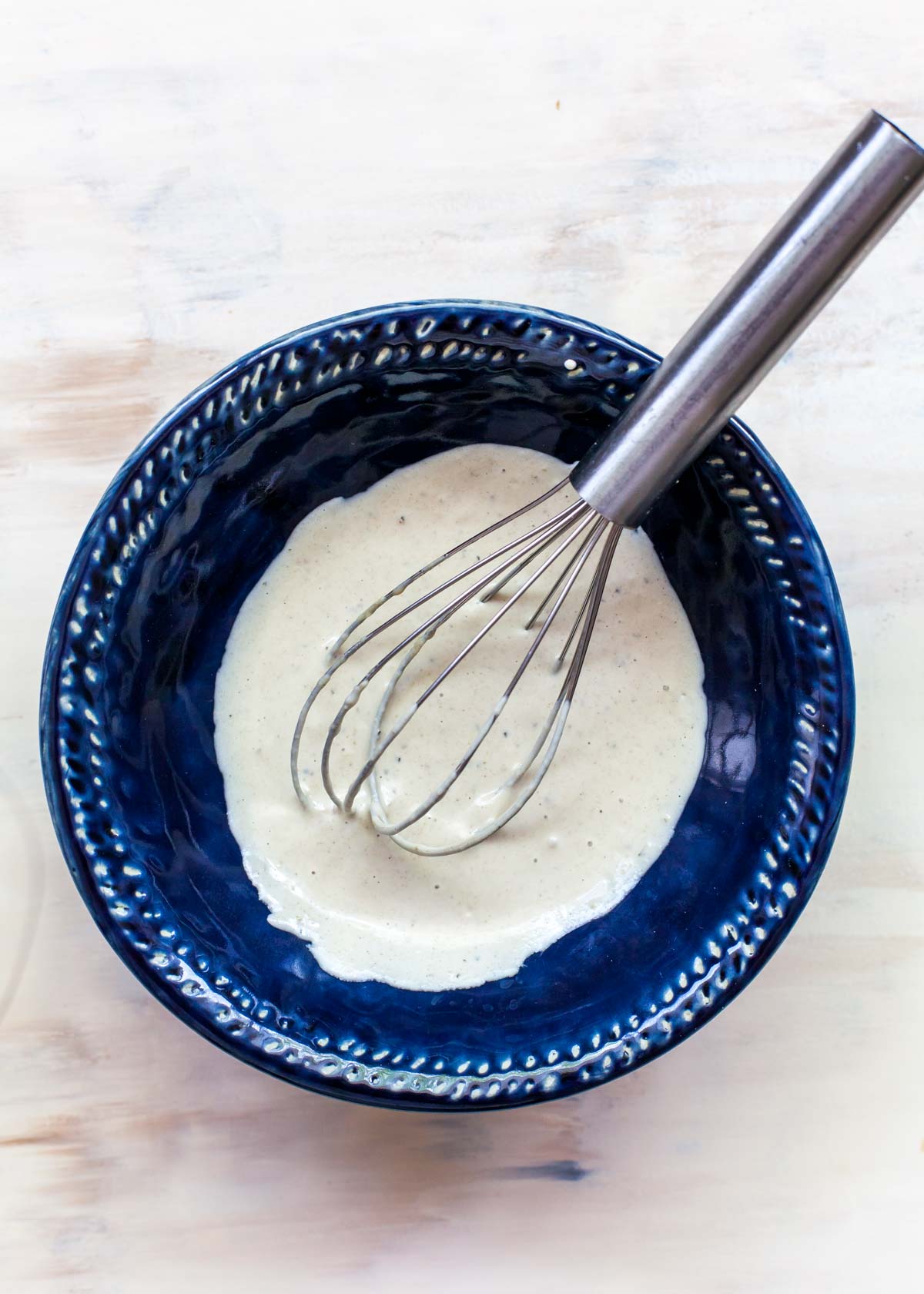 Lemon-Tahini Dressing in a blue bowl with a whisk