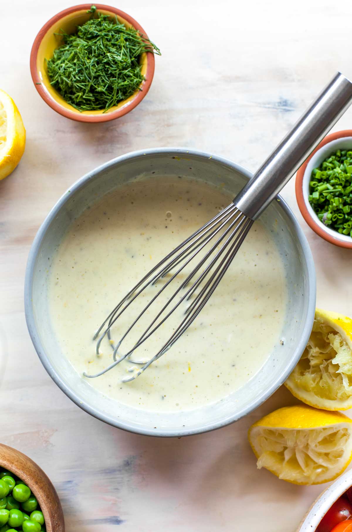 Mayonnaise, lemon juice, and olive oil whisked together in a grey bowl