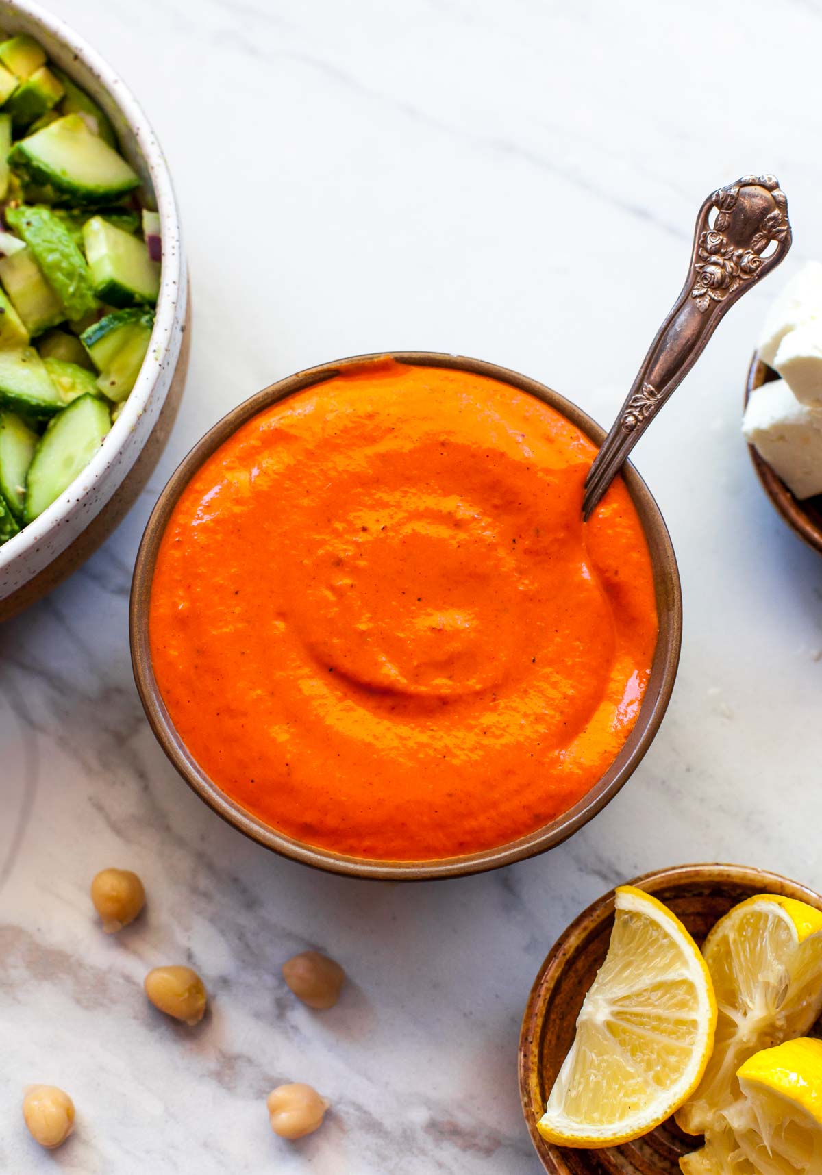 Roasted red pepper sauce in a gold bowl with a spoon resting on the right side