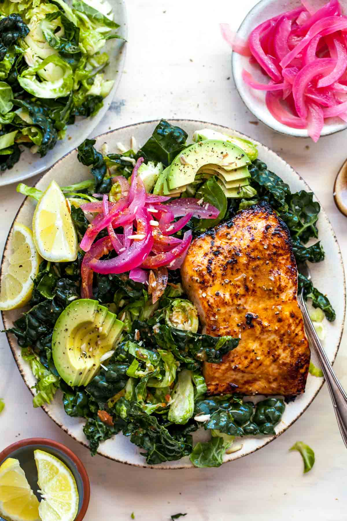 miso-glazed salmon fillet over kale and shredded brussels sprouts on a tan plate
