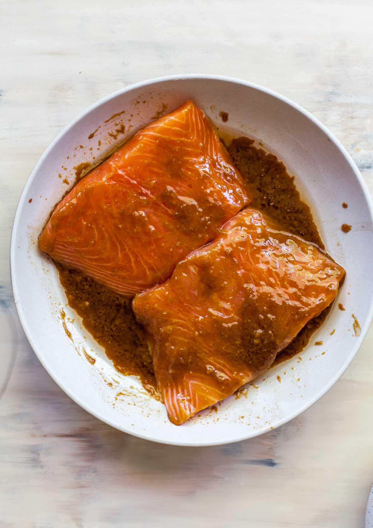 Raw salmon fillets in a bowl covered in miso marinade