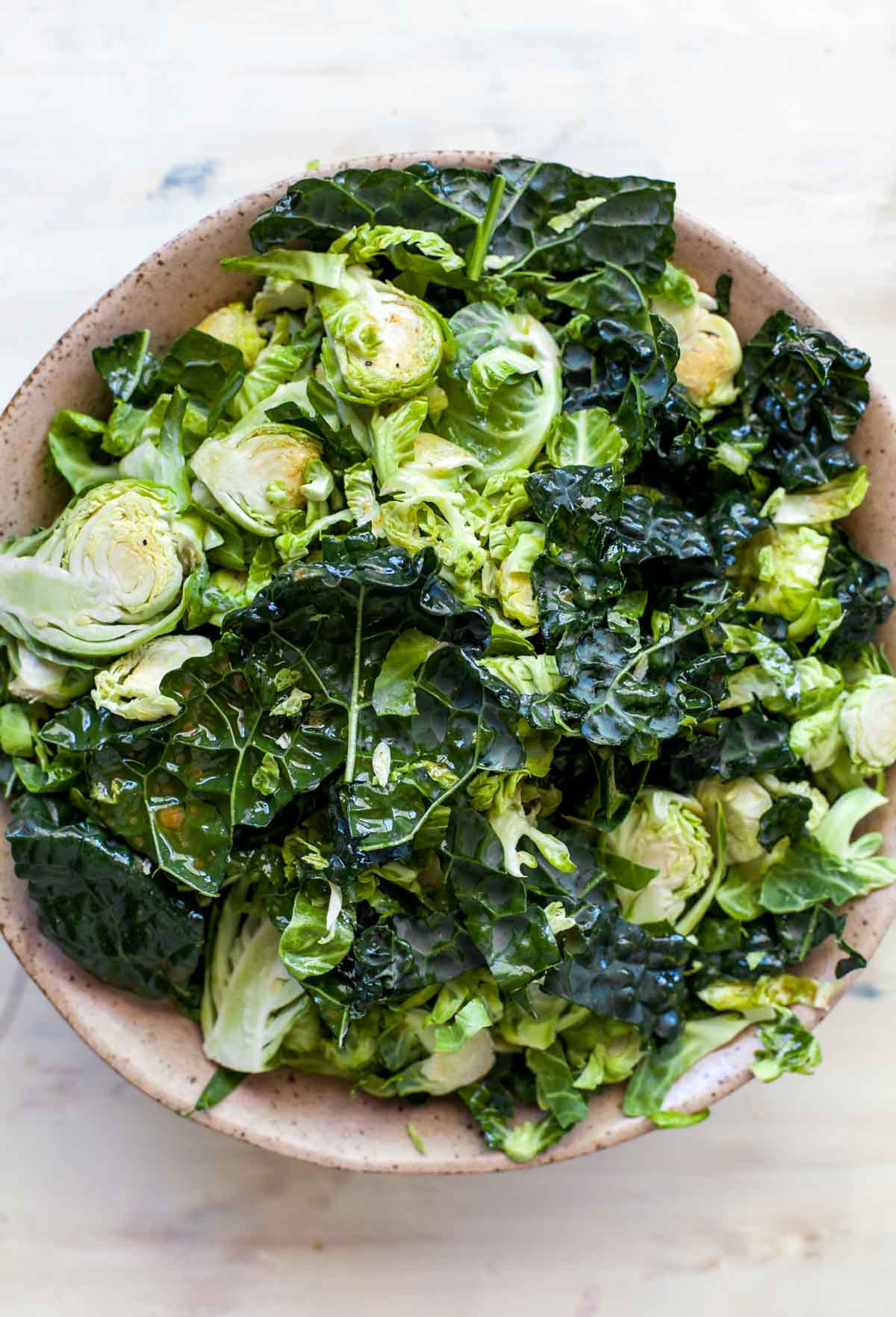 Shredded Brussels sprouts and chopped kale in a large tan bowl