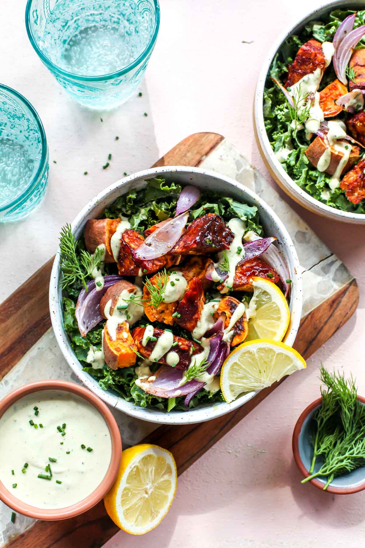 Cubes of tempeh over kale in a white bowl topped with vegan ranch dressing