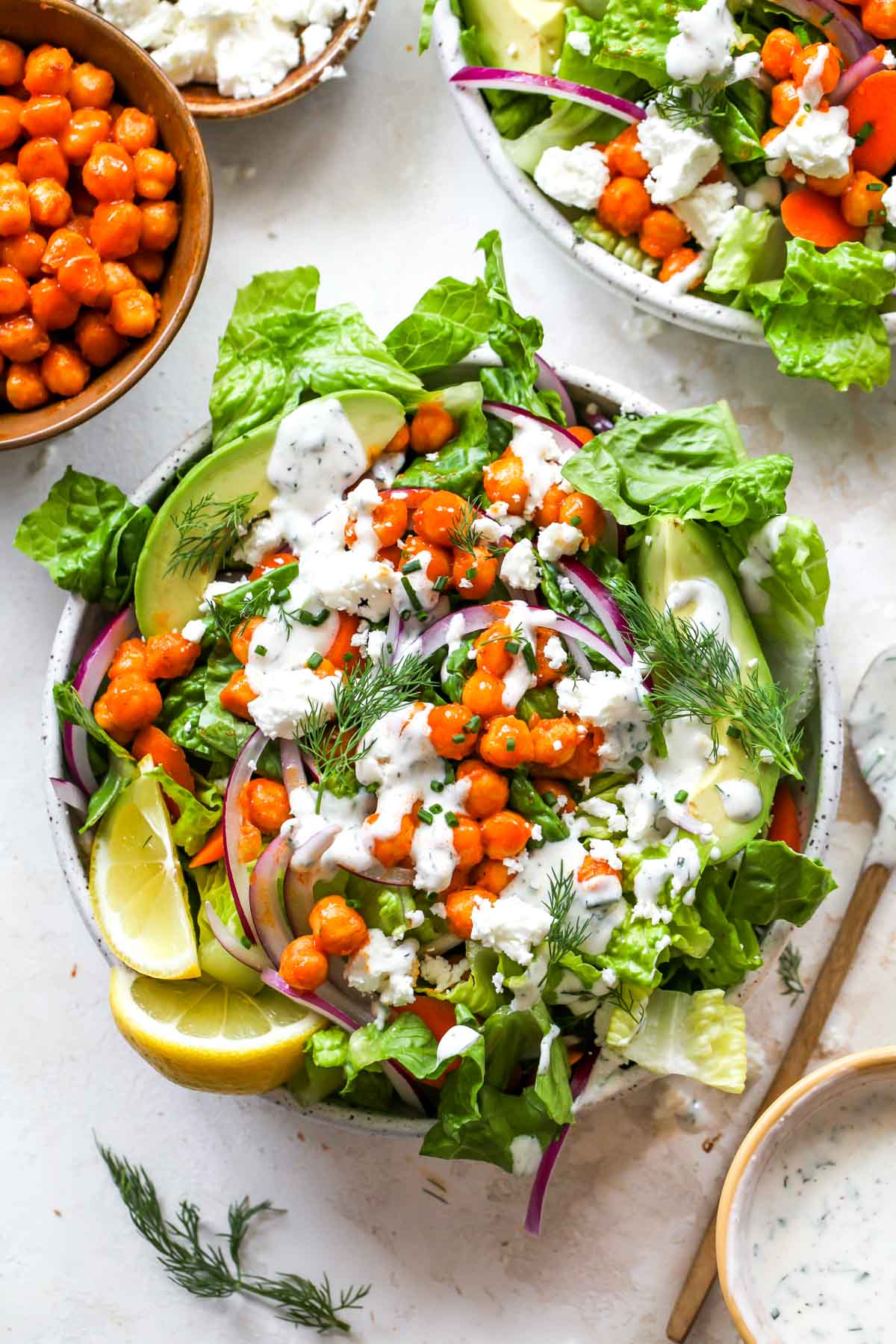 Buffalo chickpea salad in a white bowl topped with ranch dressing