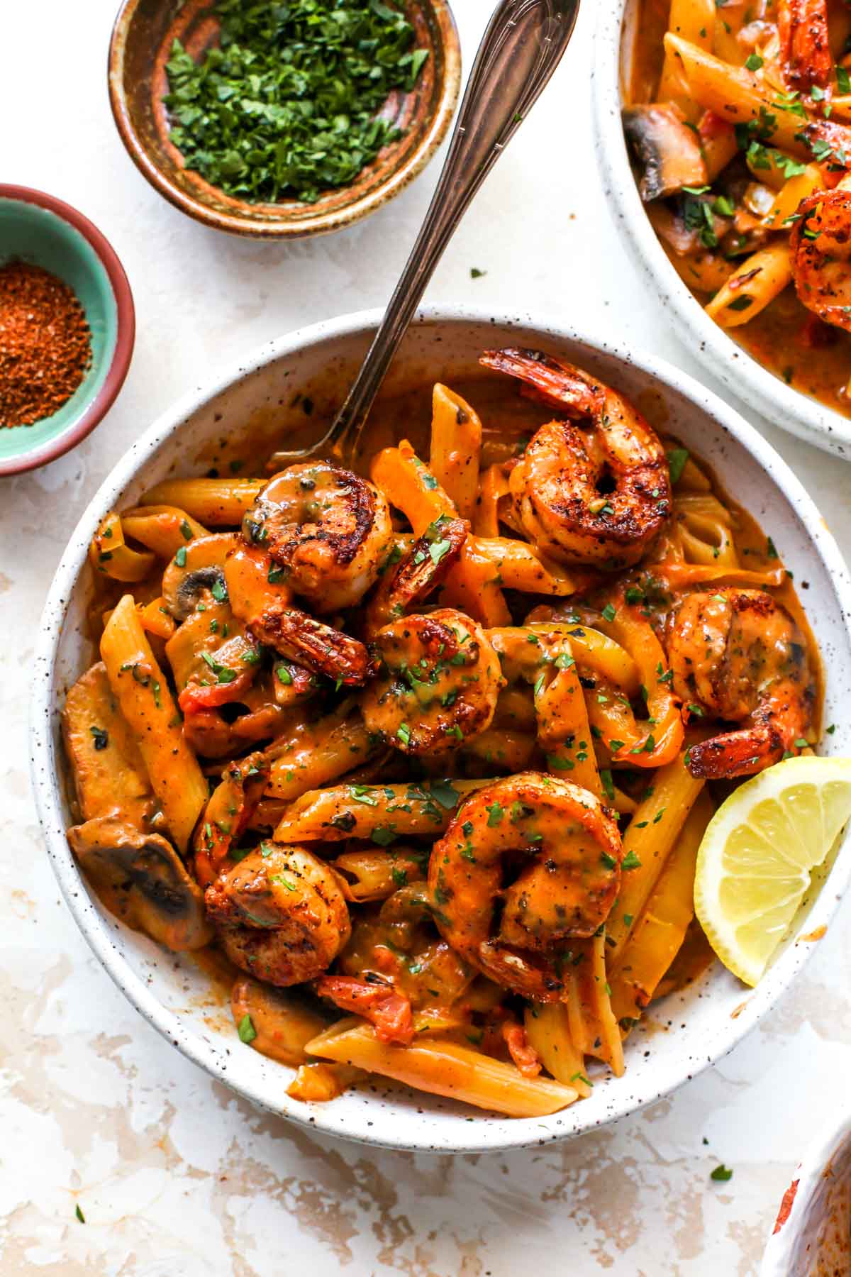 Cajun shrimp penne in a white bowl with a fork digging in