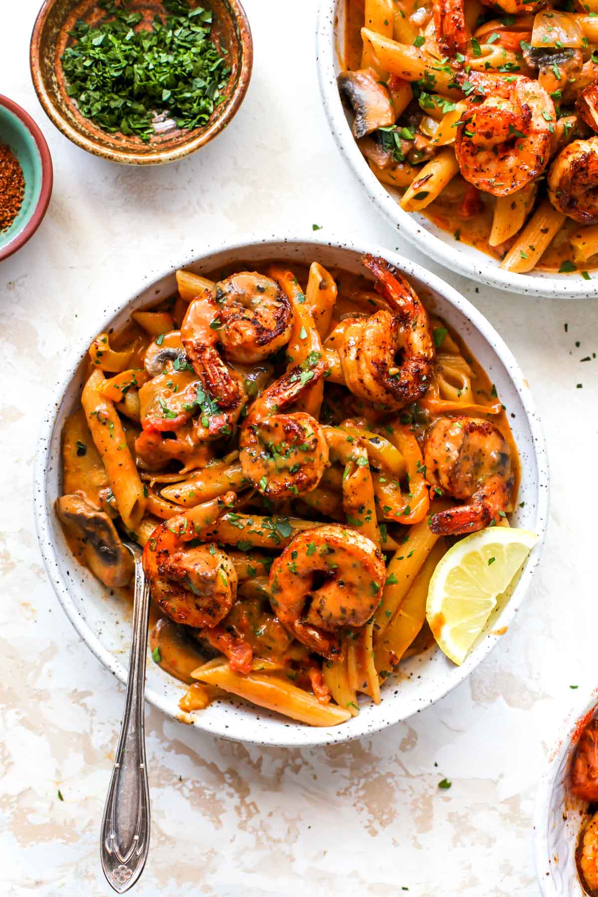 Cajun shrimp penne on a white plate with a fork resting on the bottom left