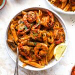 Creamy Cajun Shrimp Pasta in a white bowl with a lemon wedge garnish