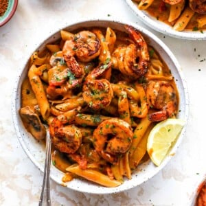 Creamy Cajun Shrimp Pasta in a white bowl with a lemon wedge garnish