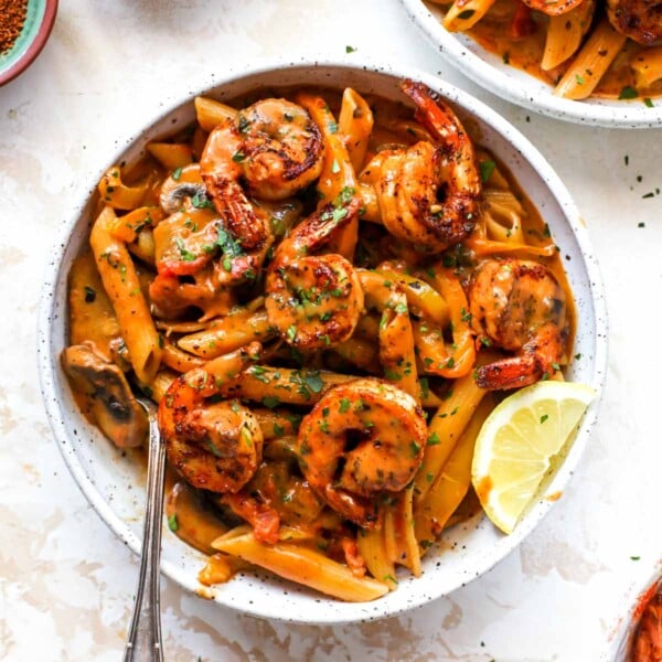 Creamy Cajun Shrimp Pasta in a white bowl with a lemon wedge garnish