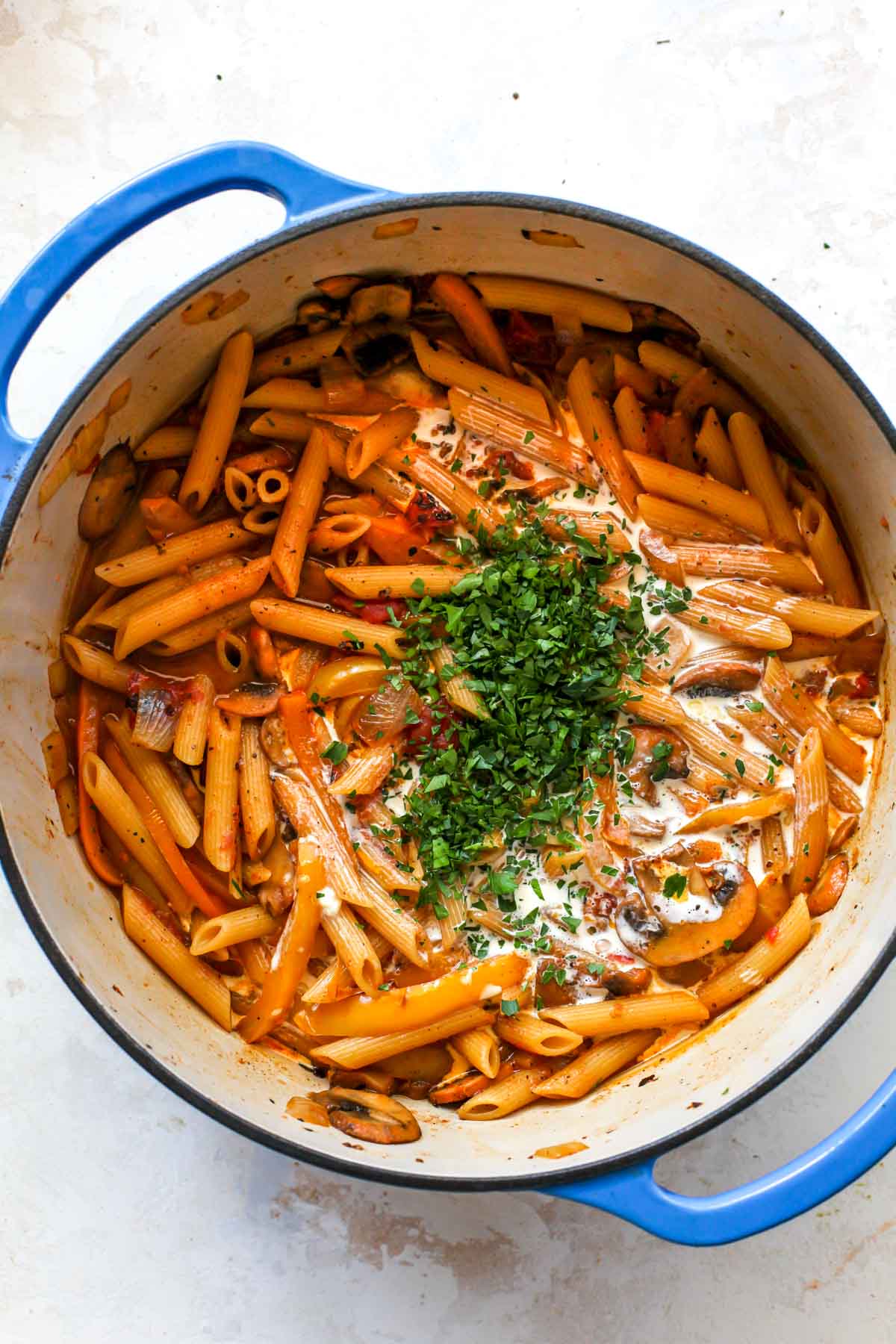 Penne pasta with cream and parsley being stirred in