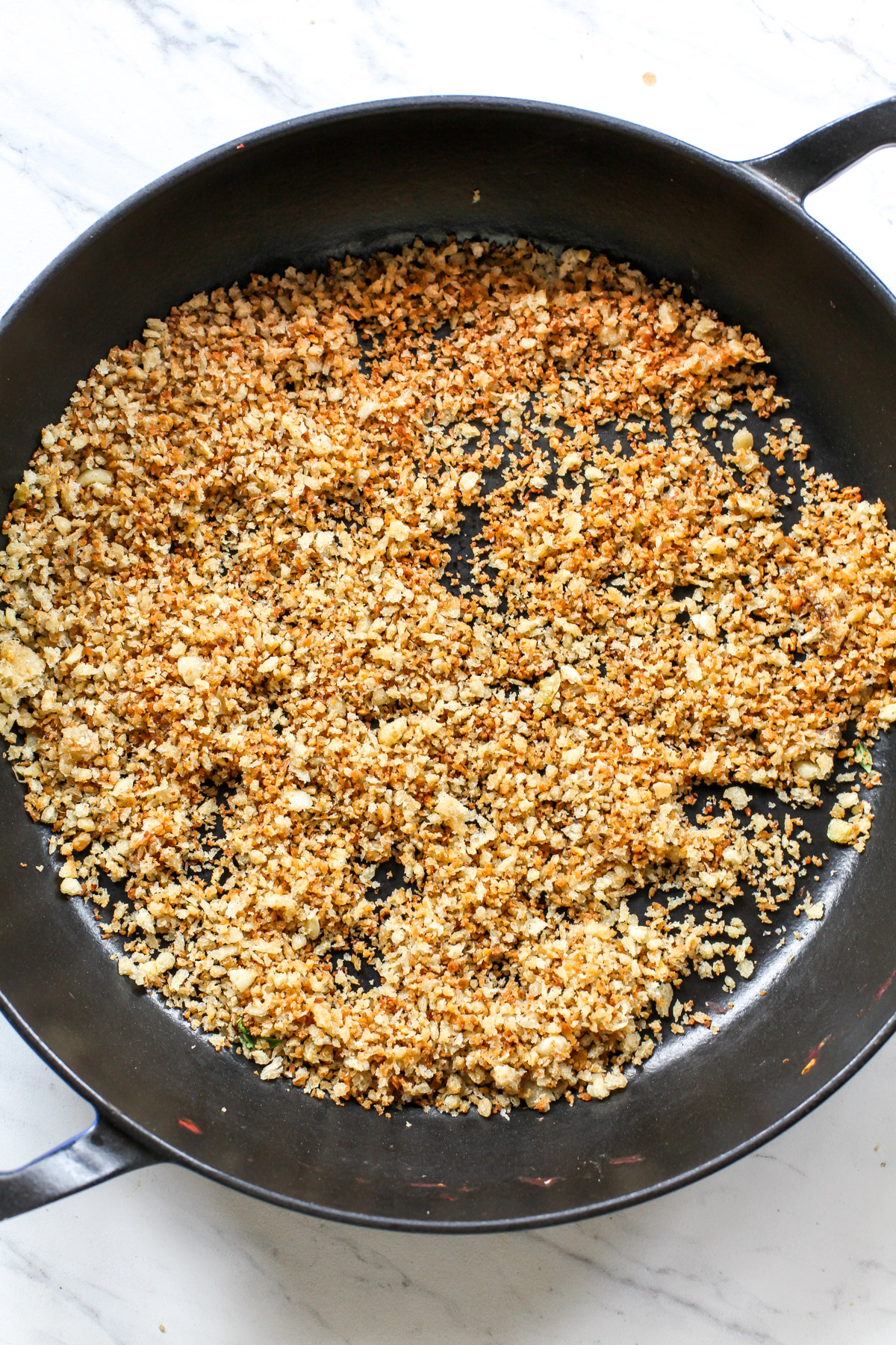 Golden panko breadcrumbs in a large black skillet