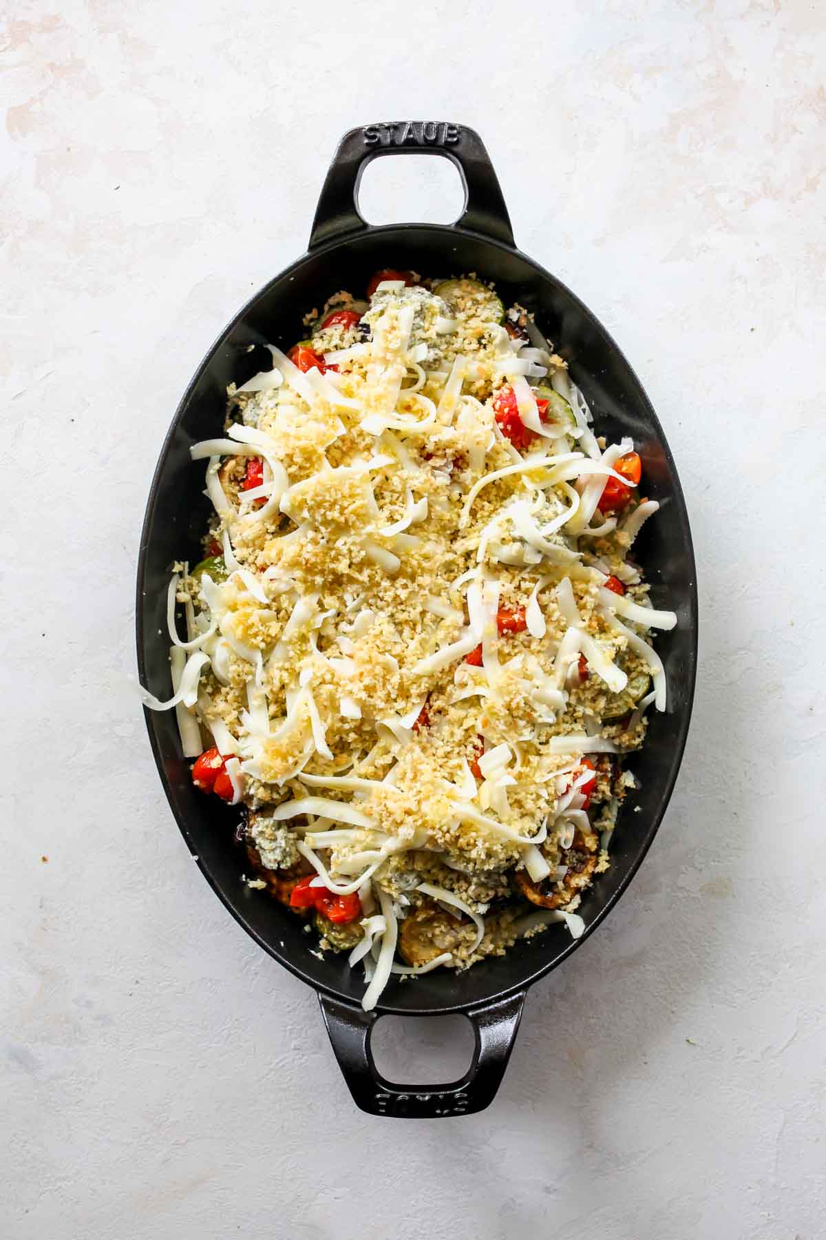Cheese and panko breadcrumbs being sprinkled over a pan of lasagna