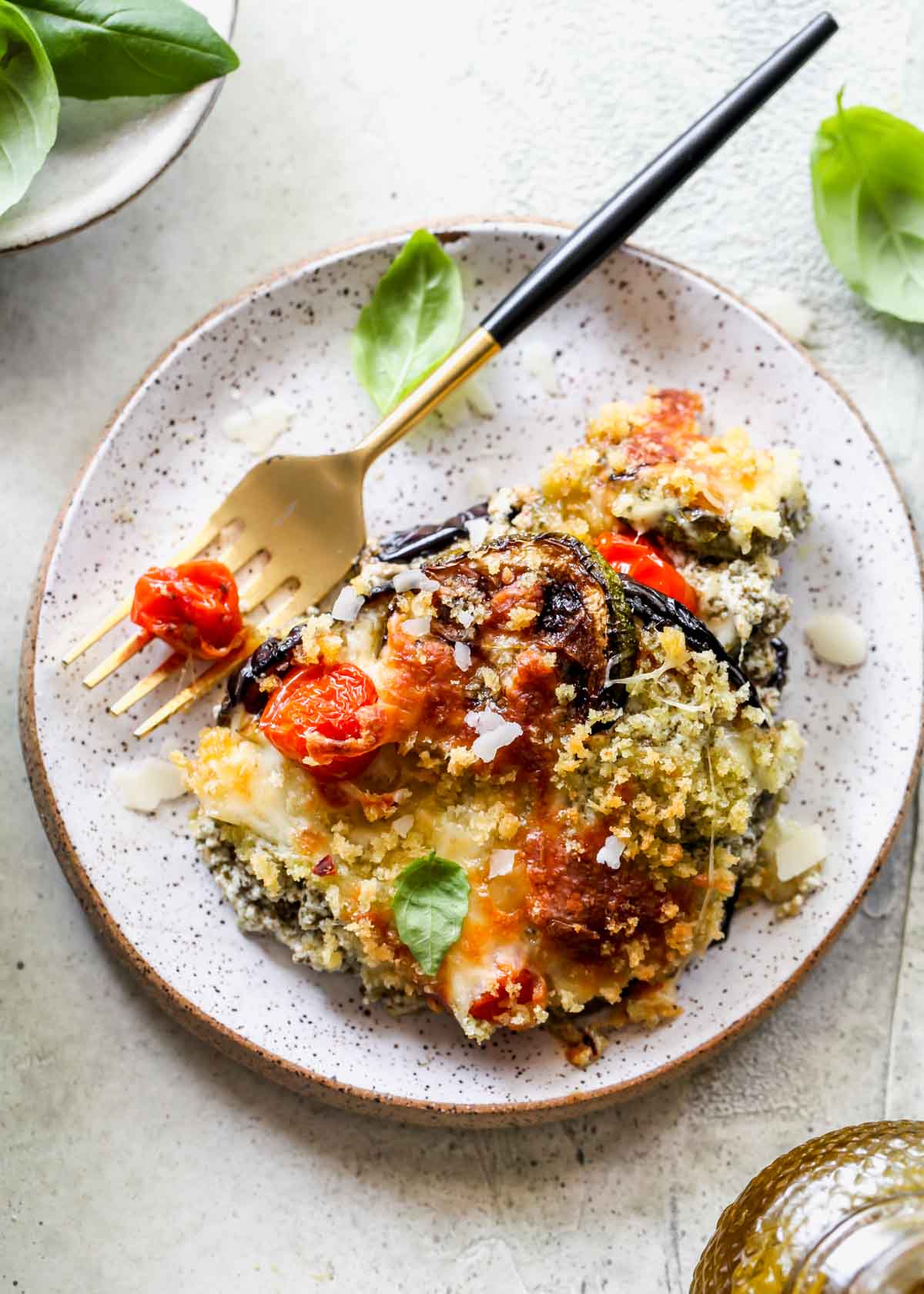 One serving of zucchini lasagna on a white plate with a fork on the side