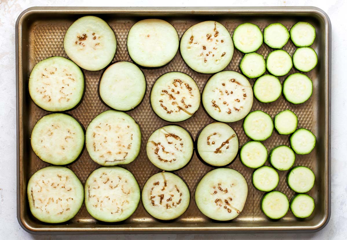 Sliced eggplant and zucchini on a large baking sheet